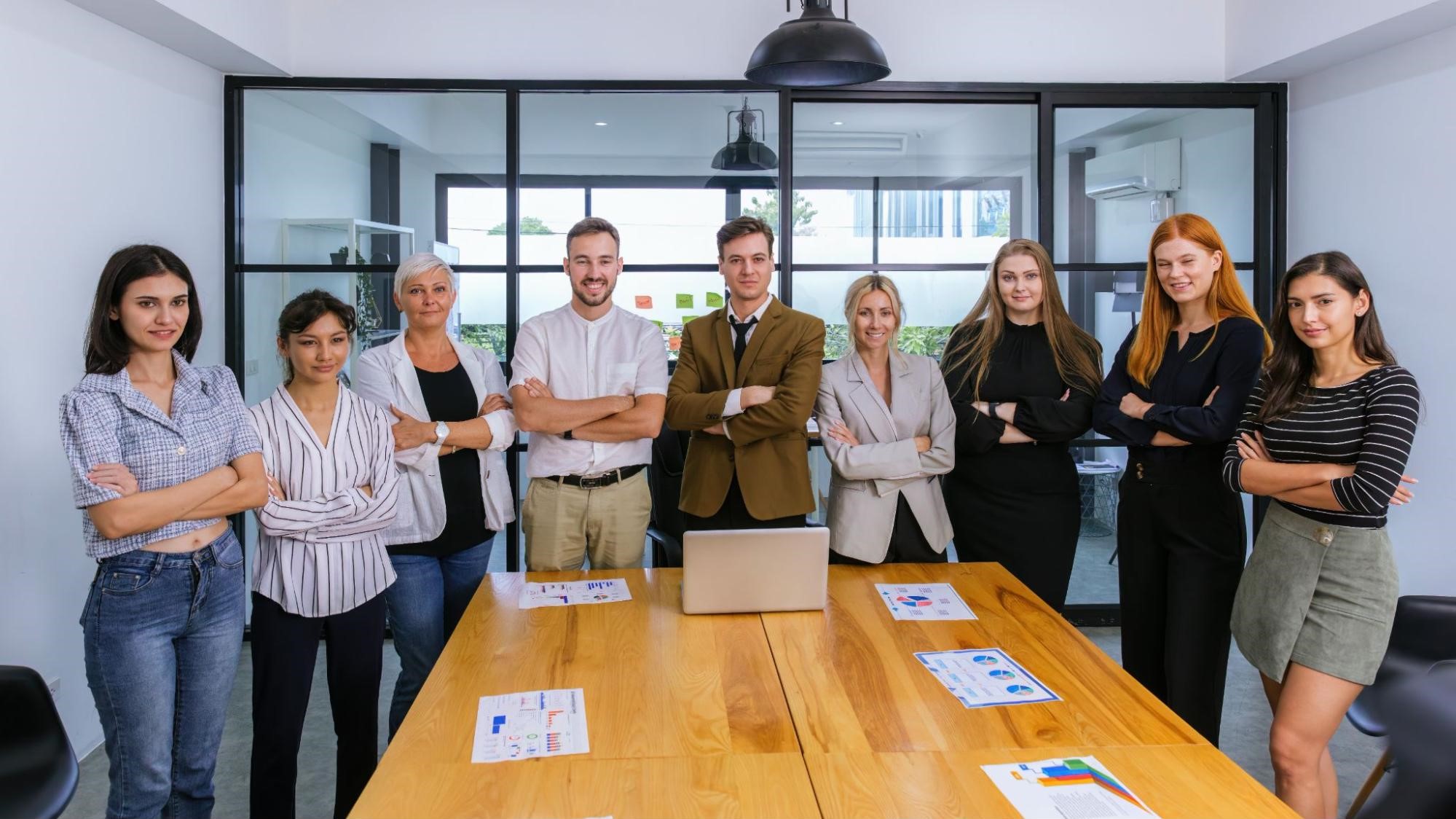 Confident marketing team standing around a meeting table, representing collaboration in content marketing strategy.