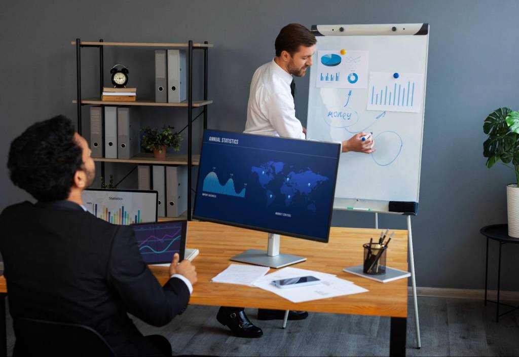 A presenter explaining data-driven strategies with a whiteboard and digital screens, showcasing predictive analytics and ROI in marketing.