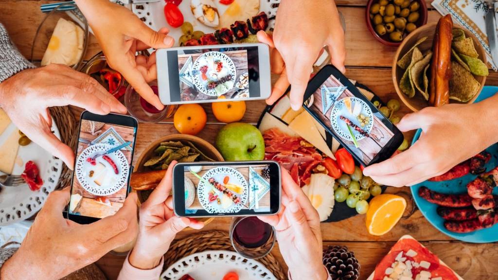 People photographing colorful food with smartphones, perfect example of repurposing content for social platforms.