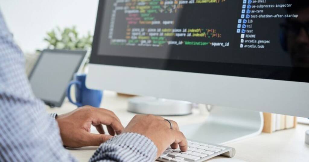 A developer coding on a computer screen with clean HTML structure and optimized code, ensuring better SEO performance and search engine indexing.