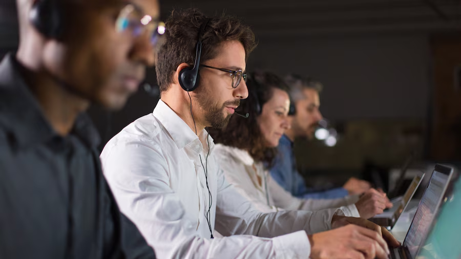 Contact center workers having a meeting in the office, with computers in front of them