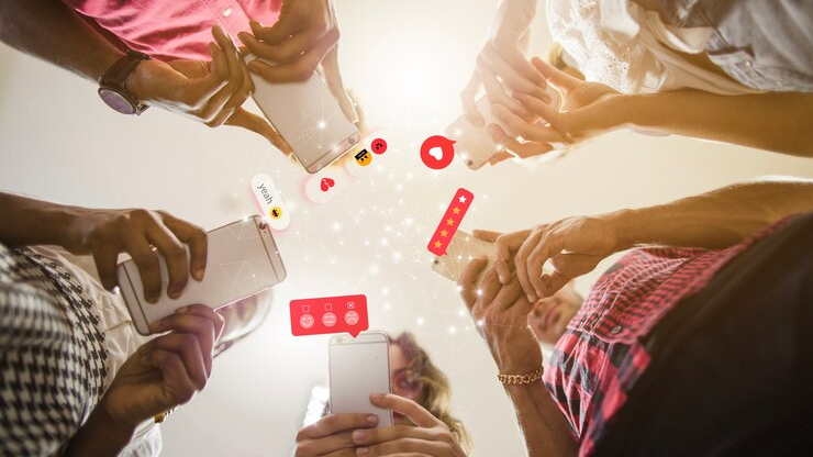 A group of people using smartphones with social media icons, showcasing the rising marketing trend for 2025 in social media engagement.