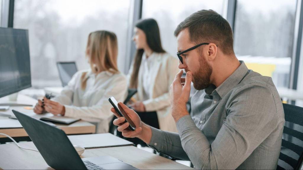 Focused professional analyzing his LinkedIn feed on a smartphone, reflecting on changes to post visibility and engagement.