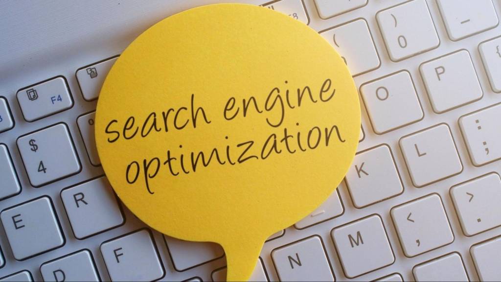 Yellow speech bubble with the words search engine optimization placed on a computer keyboard, symbolizing SEO strategy.