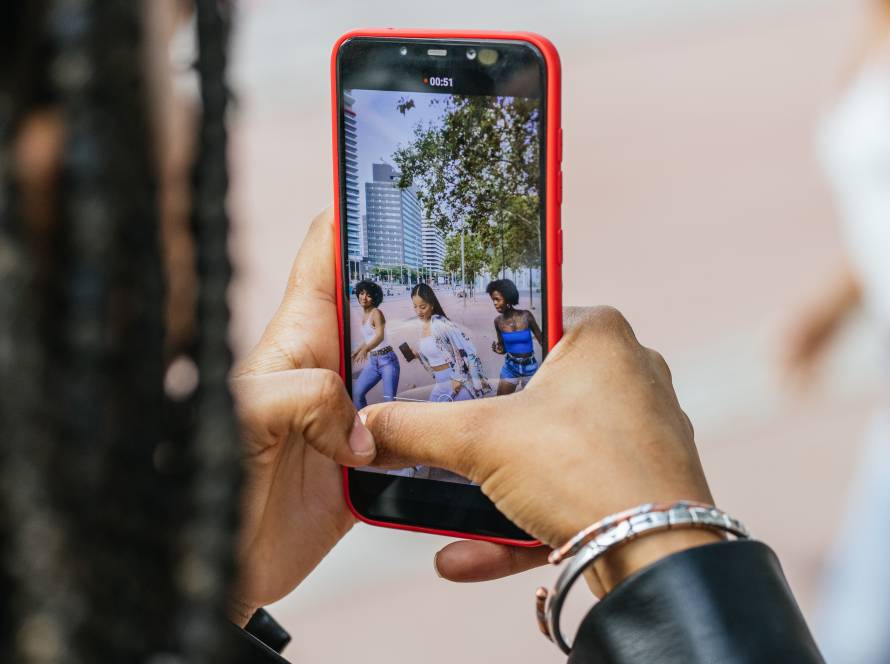 Group of young women dancing outdoors while being recorded on a smartphone for a TikTok video in Latin America.
