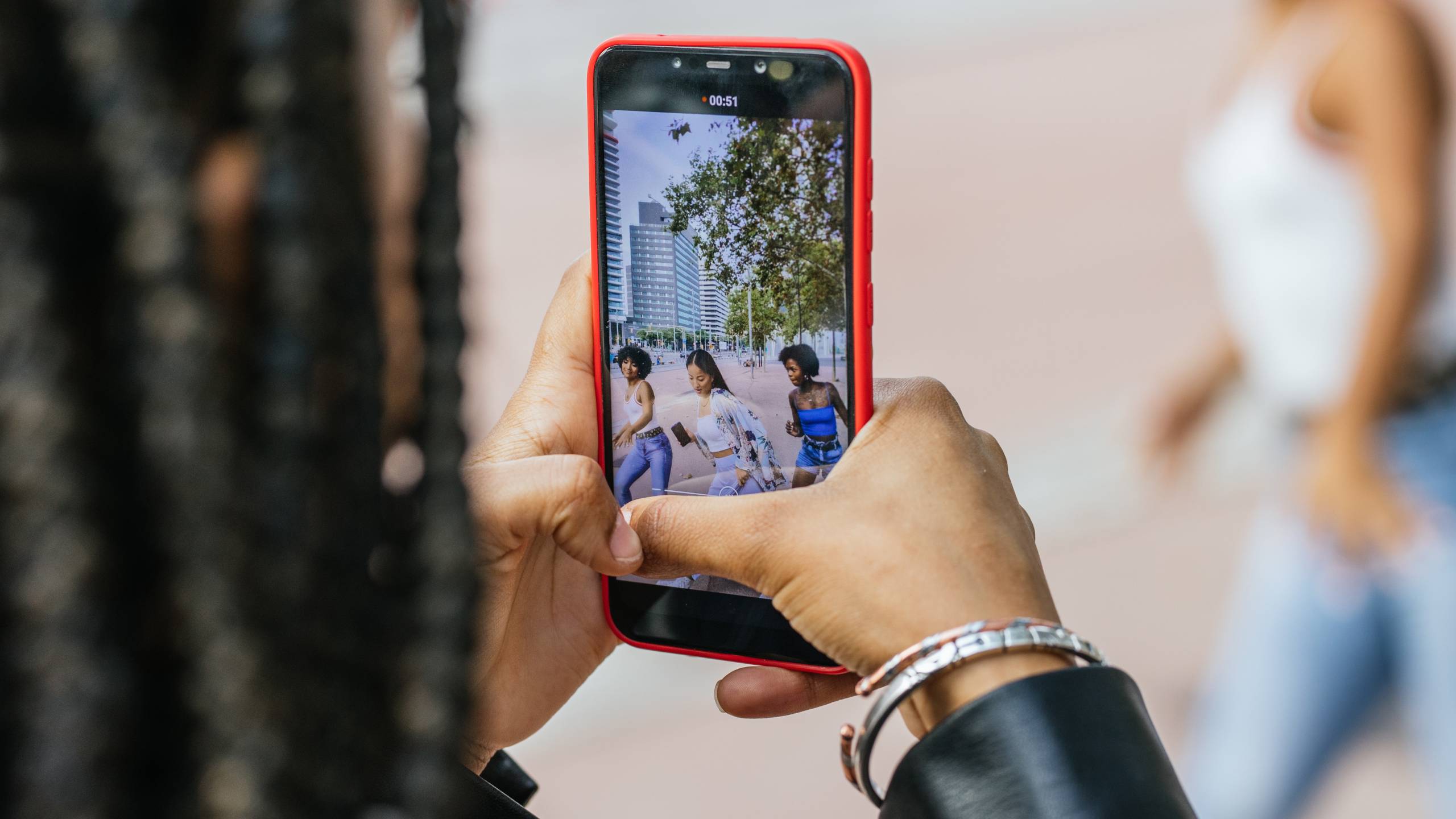 Group of young women dancing outdoors while being recorded on a smartphone for a TikTok video in Latin America.