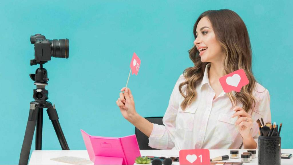 Beauty influencer recording video with camera while holding social media engagement icons
