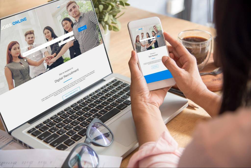 Businesswoman testing a mobile-friendly website on laptop and smartphone for SEO performance.