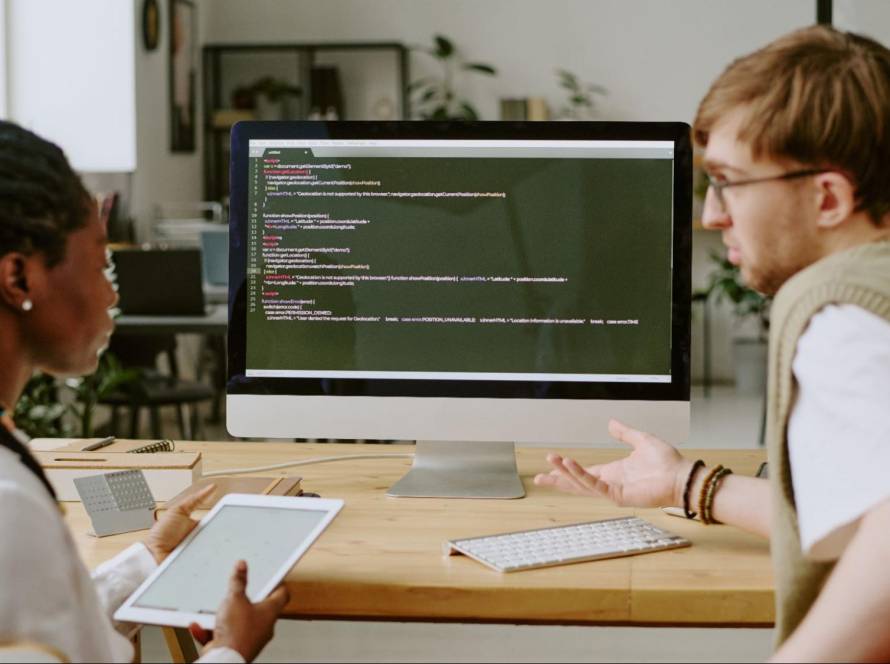 Two developers reviewing website code and discussing SEO-friendly solutions.