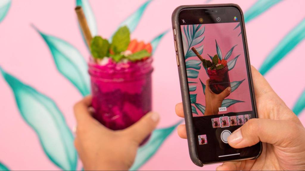 A person photographing a colorful drink for Instagram marketing content, representing visual engagement and organic content creation in 2025 trends.