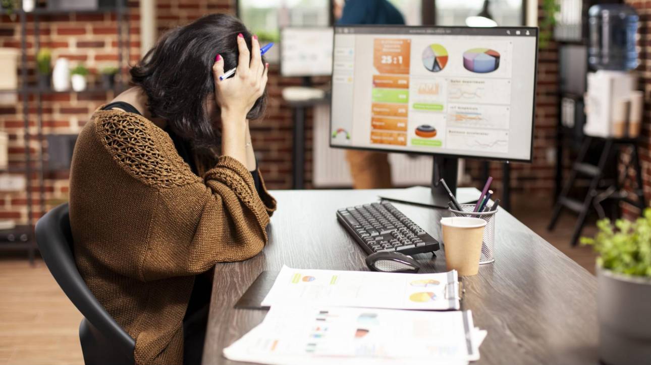 Frustrated woman at desk reviewing marketing analytics showing the challenge of working without a clear digital marketing strategy.