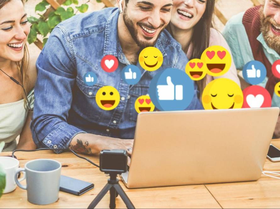 Young adults creating social media content on a laptop with engagement emojis, illustrating how hashtags help increase reach and interaction in 2025