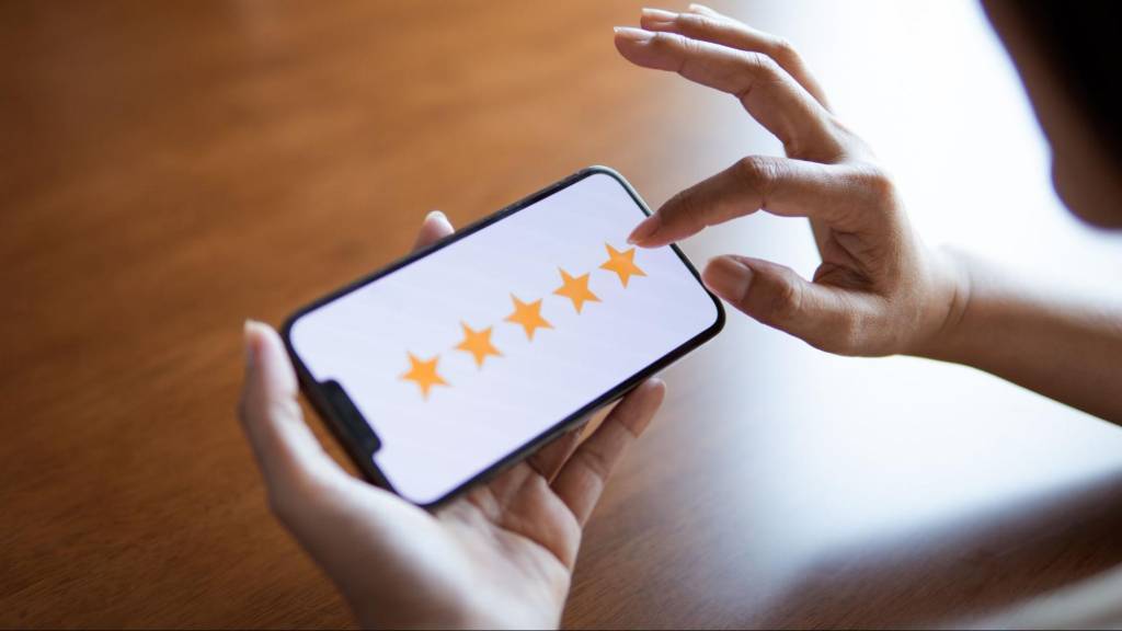Customer leaving a five-star review on a smartphone, showing how online ratings impact local SEO and trust for Florida businesses.