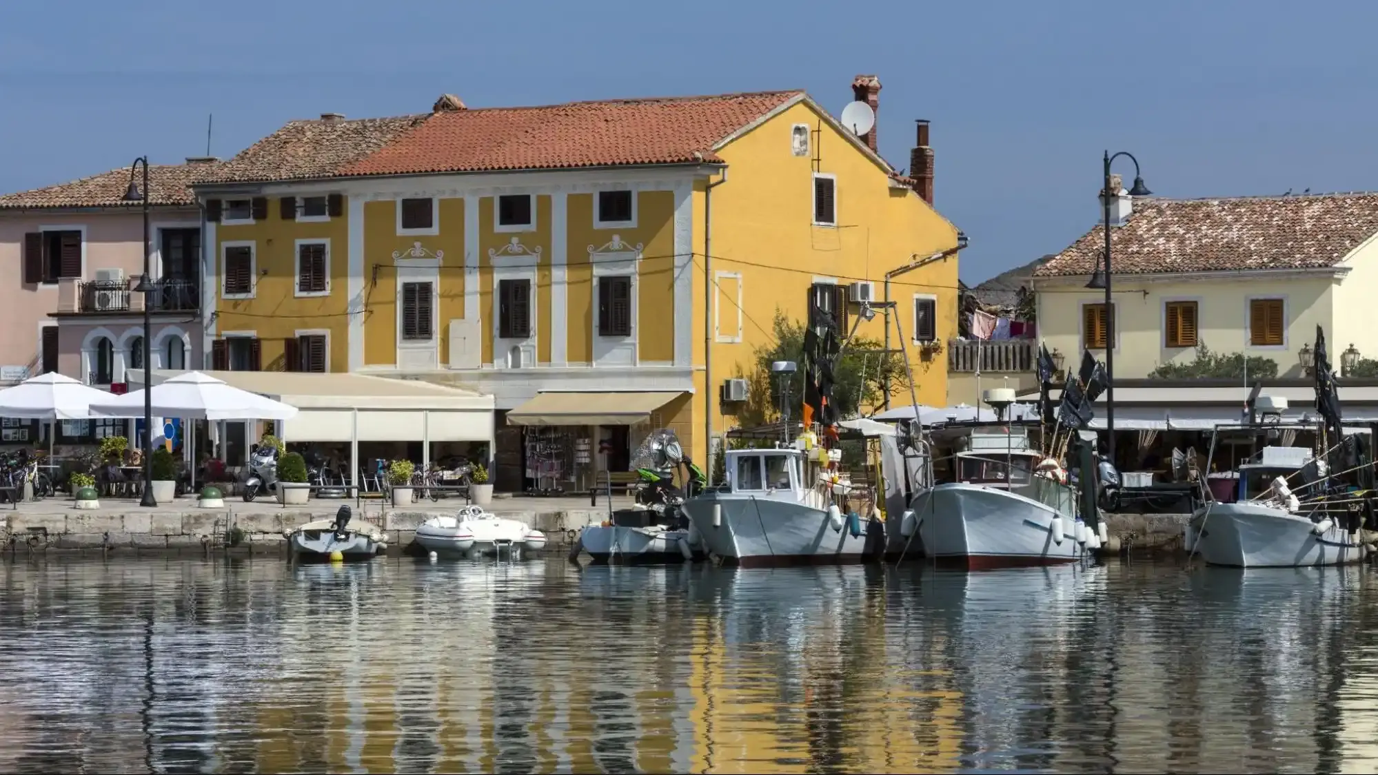 A sun-drenched coastal harbor with yellow buildings and moored boats, illustrating a high-authority hospitality entity in a Florida-style waterfront setting.