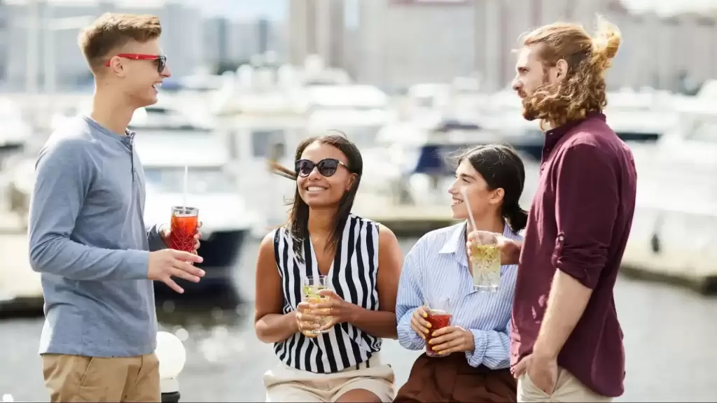 A group of young adults laughing and talking at a Florida marina with drinks, representing the authentic local experiences that AI search engines prioritize for conversational "lifestyle" queries.