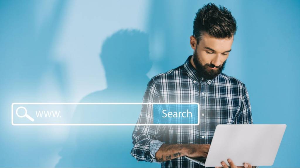 A man using a laptop with a glowing search bar graphic overlaid, representing a user making a high-commercial intent search for local services.